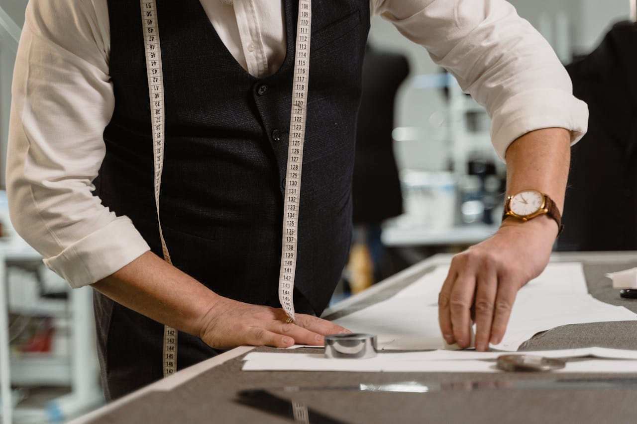 An experienced tailor measuring fabric on a workspace, showcasing precision and craftsmanship.